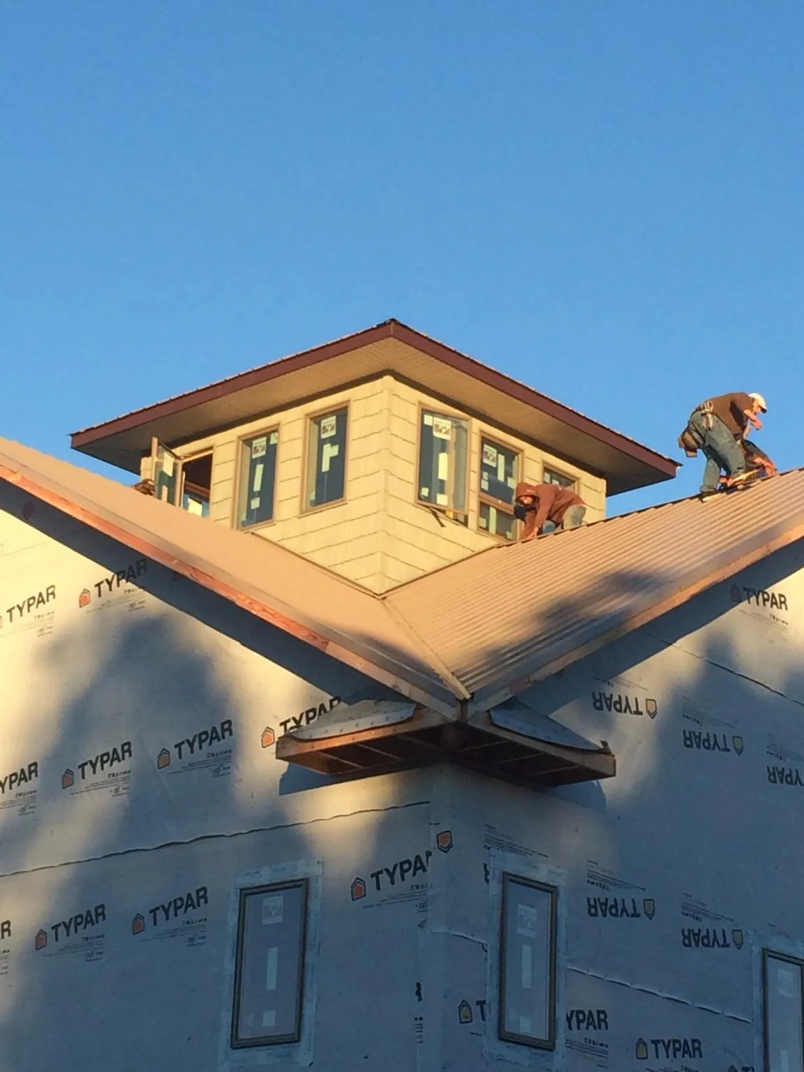 Roofers working around a rooftop cupola on a new metal roof at sunset — Roof Waterproofing in Henderson by Roofing Brothers